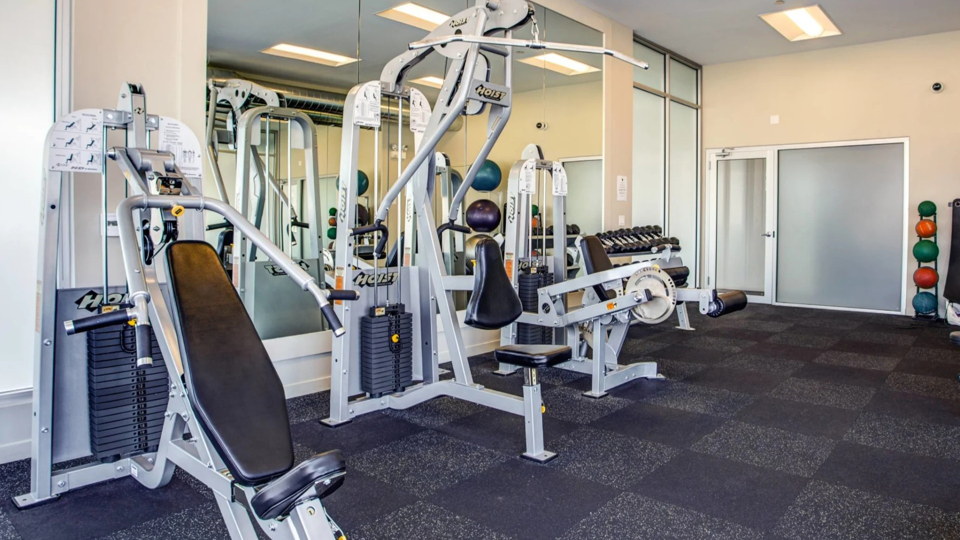 Resident weight room at 13thirteen Randolph Street Lofts offering Hoist machines, benches, medicine balls, and free weights in a clean, modern setting
