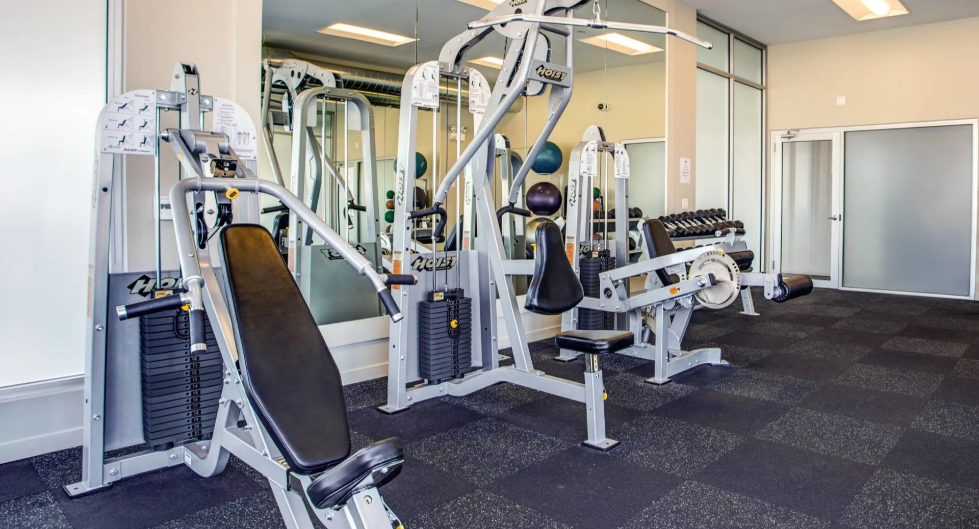 Resident weight room at 13thirteen Randolph Street Lofts offering Hoist machines, benches, medicine balls, and free weights in a clean, modern setting