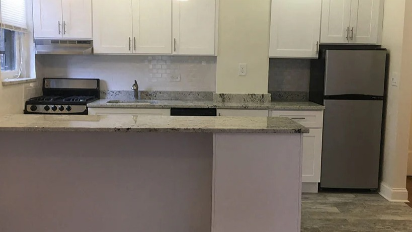 Open-concept kitchen with a breakfast bar, white cabinetry, and modern appliances, ideal for entertaining at 14 West Elm Apartments in Chicago