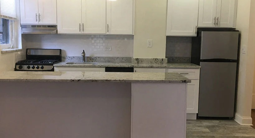 Open-concept kitchen with a breakfast bar, white cabinetry, and modern appliances, ideal for entertaining at 14 West Elm Apartments in Chicago