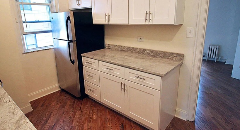 Recently renovated kitchen featuring white cabinets, granite countertops, and stainless steel refrigerator at 14 West Elm Apartments in Chicago