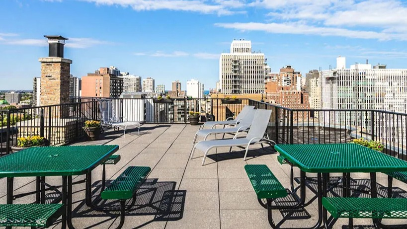 Rooftop dining area featuring green picnic tables and benches, perfect for outdoor meals with city views at 14 West Elm Apartments in Chicago