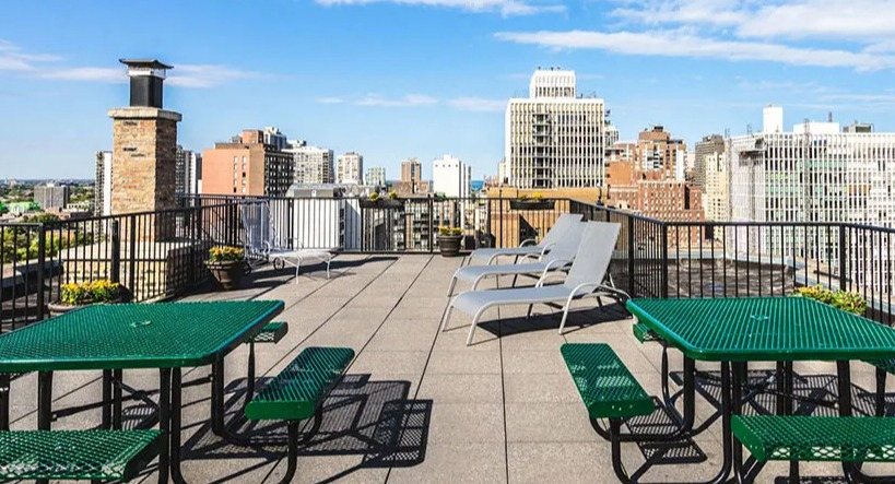 Rooftop dining area featuring green picnic tables and benches, perfect for outdoor meals with city views at 14 West Elm Apartments in Chicago