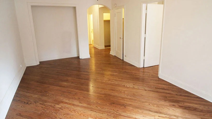 Spacious empty living room with gleaming hardwood floors, ready for personal touches at 14 West Elm Apartments in Chicago