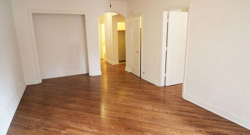 Spacious empty living room with gleaming hardwood floors, ready for personal touches at 14 West Elm Apartments in Chicago