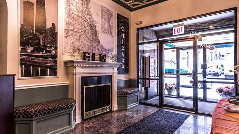 Stylish and inviting lobby entrance with Chicago-themed wall art, elegant ceiling details, and comfortable seating at 14 West Elm Apartments