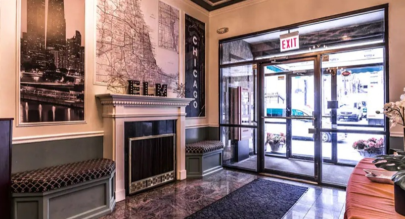 Stylish and inviting lobby entrance with Chicago-themed wall art, elegant ceiling details, and comfortable seating at 14 West Elm Apartments