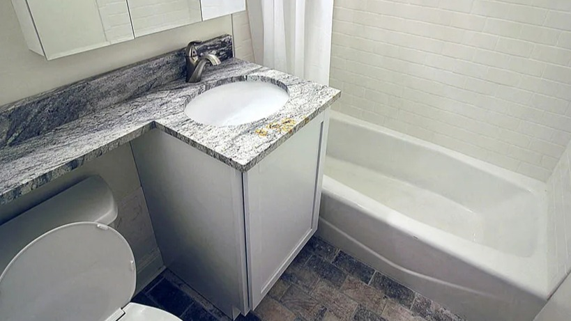 Updated bathroom with a clean white bathtub, sleek vanity with granite countertop, and modern fixtures at 14 West Elm Apartments in Chicago