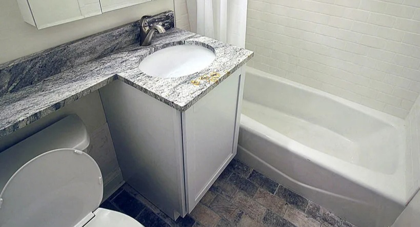 Updated bathroom with a clean white bathtub, sleek vanity with granite countertop, and modern fixtures at 14 West Elm Apartments in Chicago