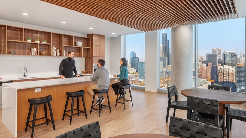 Skyline lounge with demonstration kitchen, long island, wood slat ceiling, and floor-to-ceiling windows at 1400 Wabash apartments in Chicago