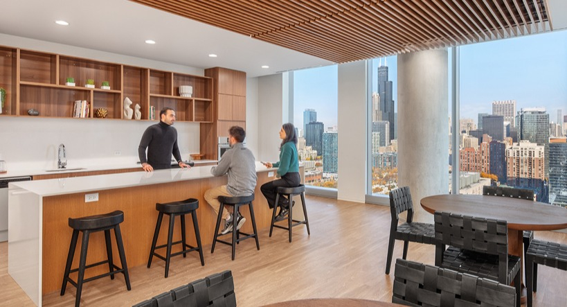 Skyline lounge with demonstration kitchen, long island, wood slat ceiling, and floor-to-ceiling windows at 1400 Wabash apartments in Chicago