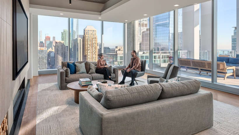 Stylish resident lounge with plush sofas, large TV wall, designer lighting, and floor-to-ceiling windows opening to a terrace at 1400 Wabash in Chicago
