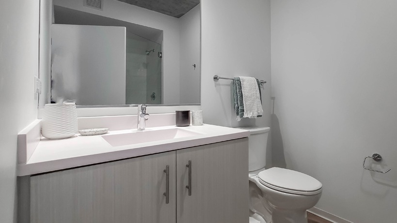 Spacious bathroom with wide vanity, soft lighting, neutral finishes, and a standard toilet at 1400 Wabash apartments in Chicago
