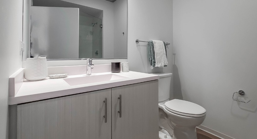 Spacious bathroom with wide vanity, soft lighting, neutral finishes, and a standard toilet at 1400 Wabash apartments in Chicago