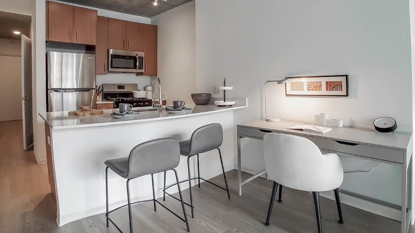 Modern kitchen with breakfast bar, stainless appliances, and an integrated work desk for WFH convenience at 1400 Wabash apartments in Chicago