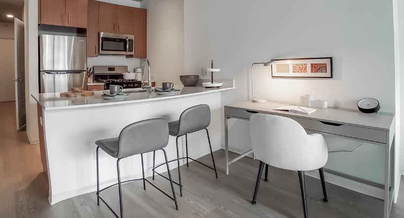 Modern kitchen with breakfast bar, stainless appliances, and an integrated work desk for WFH convenience at 1400 Wabash apartments in Chicago