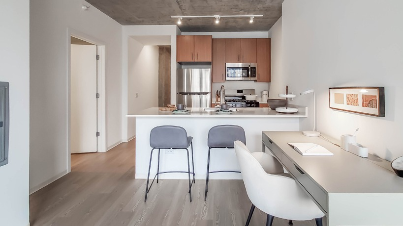 Living room with expansive windows and a dramatic Chicago skyline view, stylish sofa, and round coffee table at 1400 Wabash apartments
