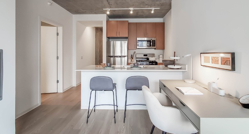 Living room with expansive windows and a dramatic Chicago skyline view, stylish sofa, and round coffee table at 1400 Wabash apartments