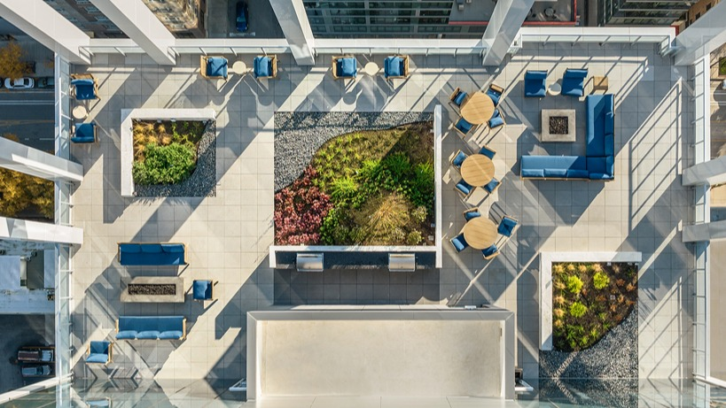 Aerial view of the rooftop skydeck with lounge seating, fire pit areas, dining tables, planters, and grill zones at 1400 Wabash apartments in Chicago