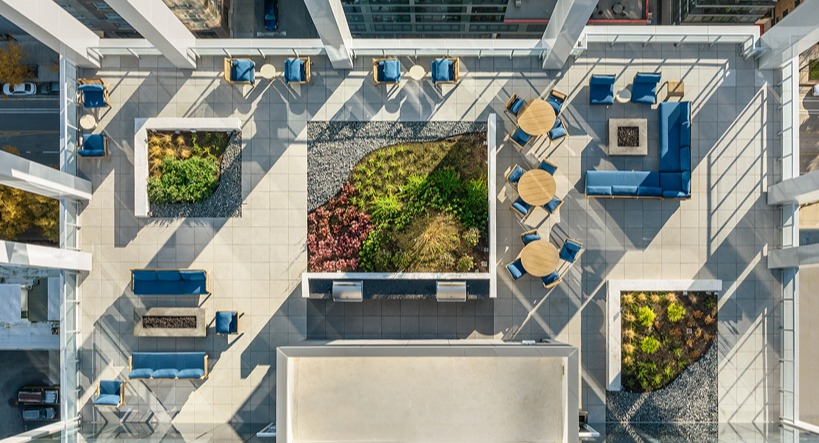 Aerial view of the rooftop skydeck with lounge seating, fire pit areas, dining tables, planters, and grill zones at 1400 Wabash apartments in Chicago