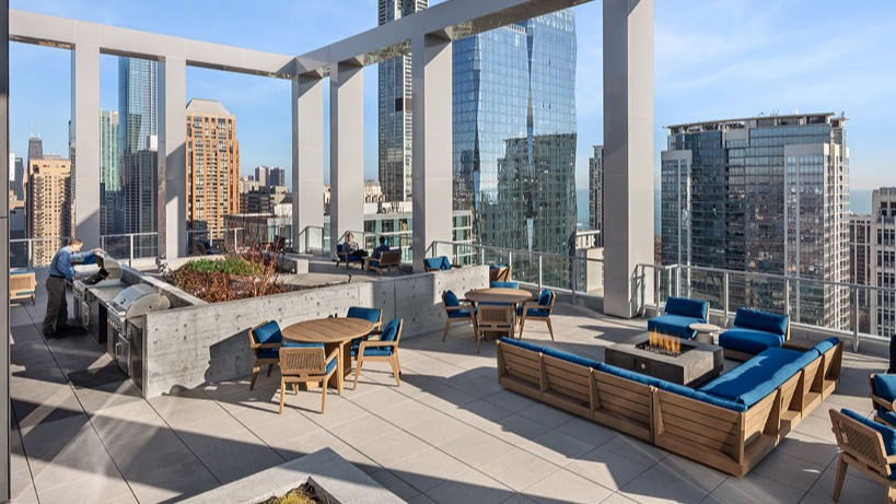 Expansive rooftop terrace with BBQ grills, dining tables, lounge seating, and panoramic city views at 1400 Wabash apartments in Chicago