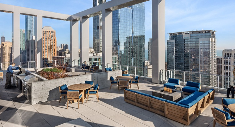 Expansive rooftop terrace with BBQ grills, dining tables, lounge seating, and panoramic city views at 1400 Wabash apartments in Chicago