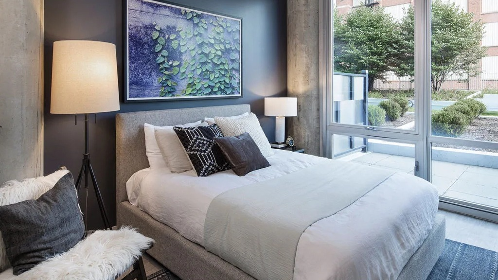 Comfortable bedroom at 1401 S. State Apartments in Chicago, featuring a cozy bed, modern decor, and direct access to an outdoor patio