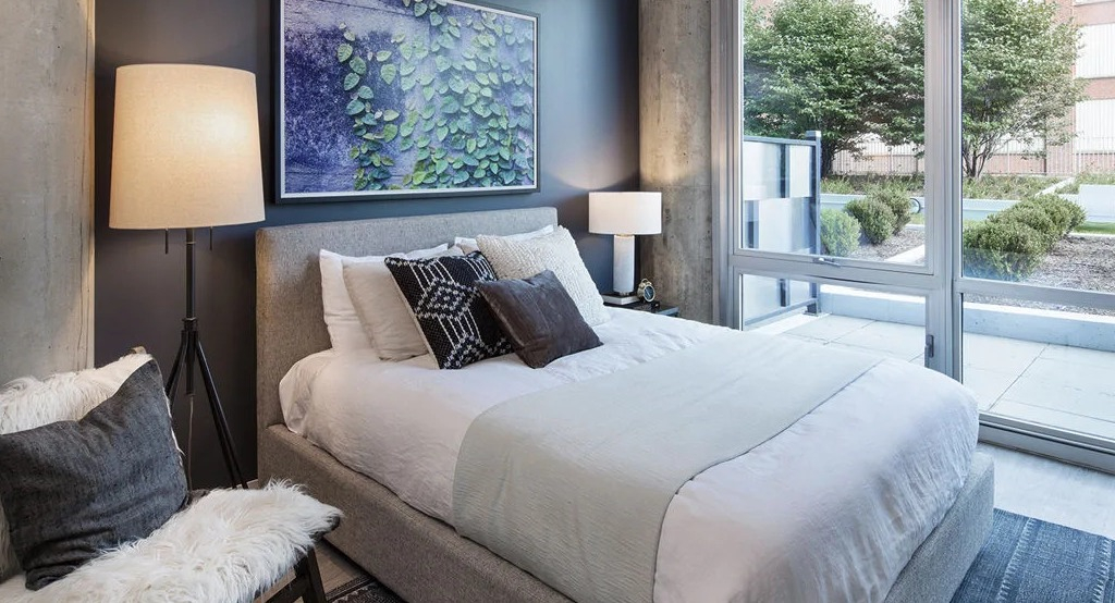 Comfortable bedroom at 1401 S. State Apartments in Chicago, featuring a cozy bed, modern decor, and direct access to an outdoor patio