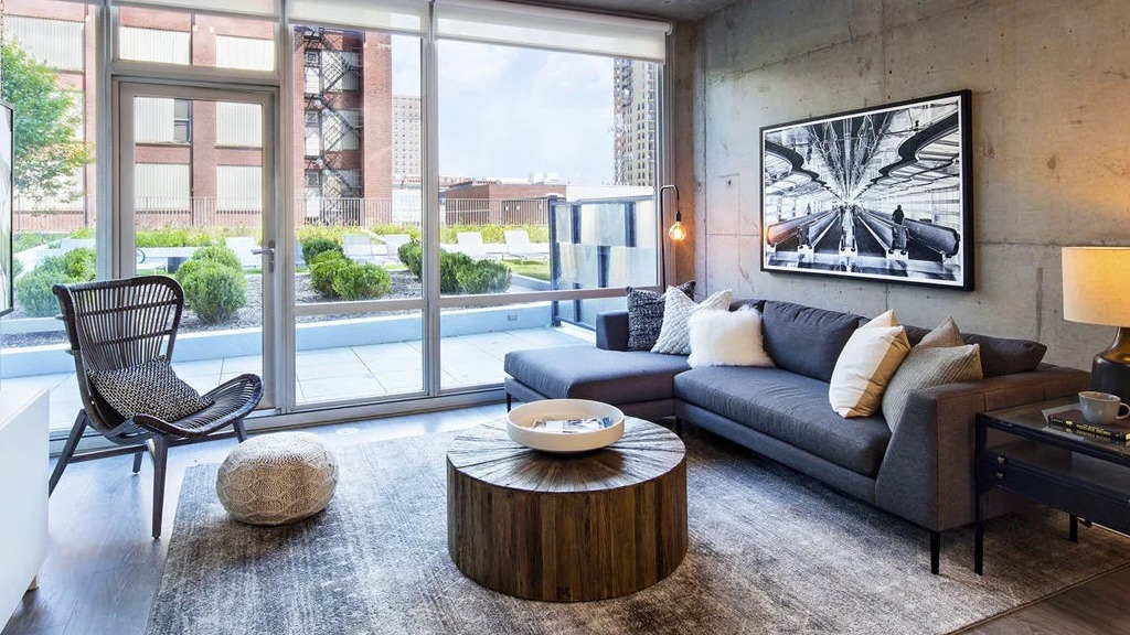 Spacious living room at 1401 S. State Apartments in Chicago, featuring a large sectional sofa, modern art, and access to an outdoor patio