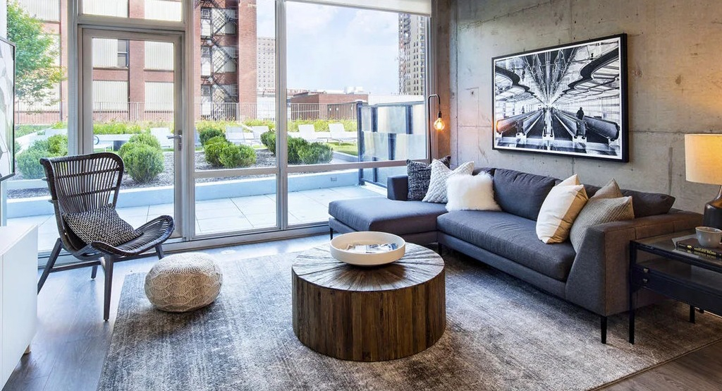 Spacious living room at 1401 S. State Apartments in Chicago, featuring a large sectional sofa, modern art, and access to an outdoor patio