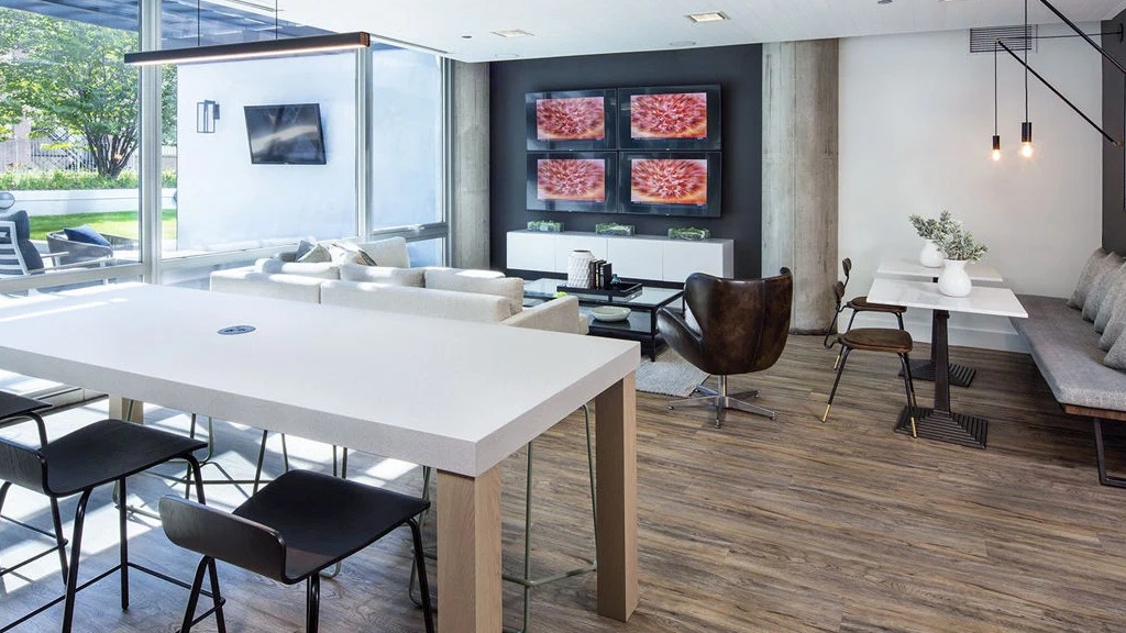 Spacious resident lounge at 1401 S. State Apartments in Chicago, featuring communal tables, comfortable seating, and a large entertainment wall