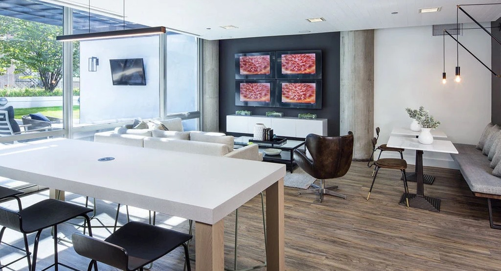 Spacious resident lounge at 1401 S. State Apartments in Chicago, featuring communal tables, comfortable seating, and a large entertainment wall