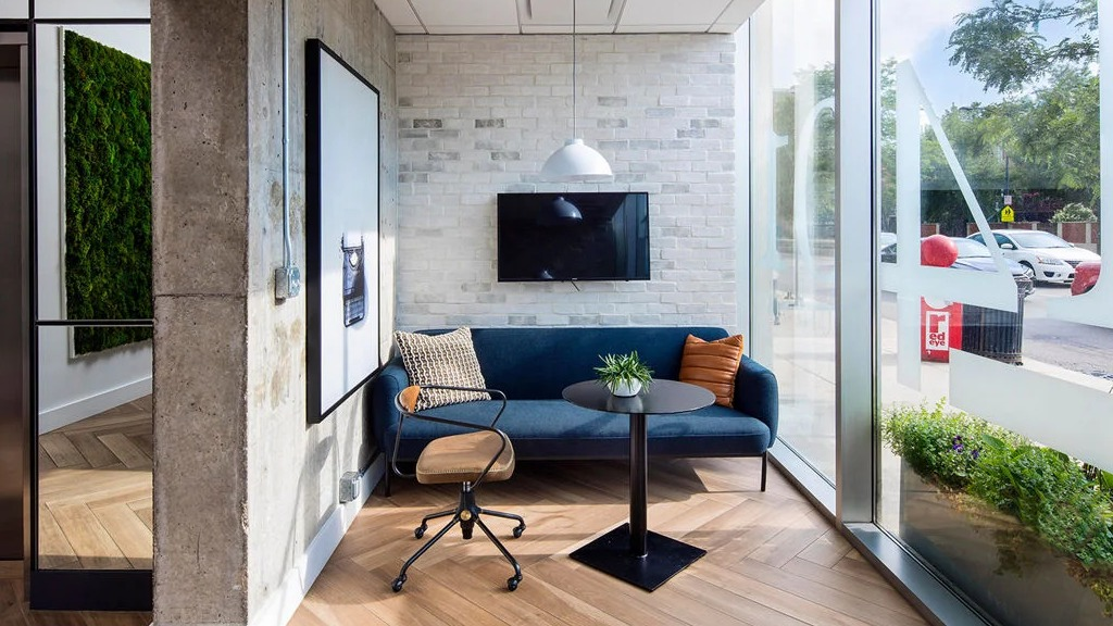 Stylish work lounge area at 1401 S. State Apartments in Chicago, featuring a comfortable sofa, desk, and large windows with street views