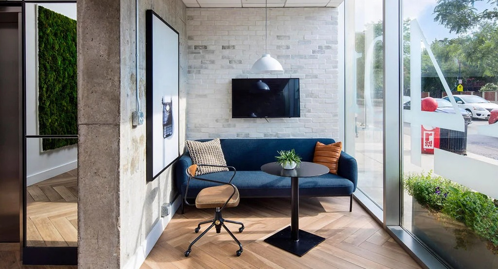 Stylish work lounge area at 1401 S. State Apartments in Chicago, featuring a comfortable sofa, desk, and large windows with street views