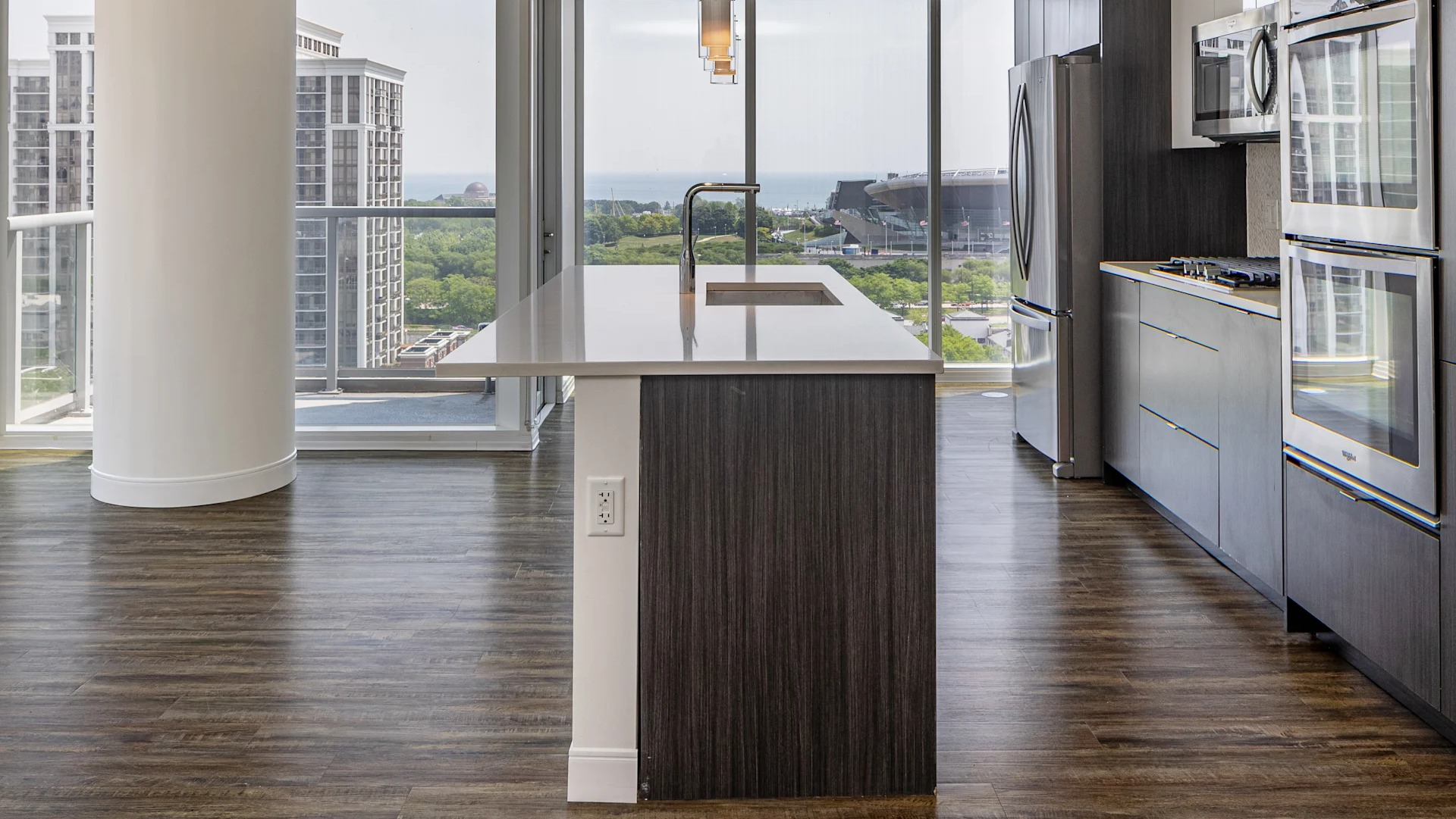 Corner kitchen with quartz island, wall ovens, and floor-to-ceiling windows with lake and skyline views at 1407 on Michigan in Chicago