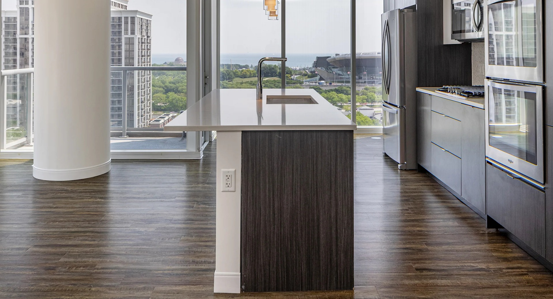 Corner kitchen with quartz island, wall ovens, and floor-to-ceiling windows with lake and skyline views at 1407 on Michigan in Chicago