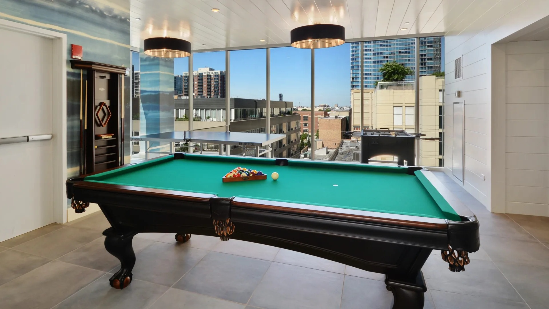 Resident clubroom with billiards table, statement pendants, and floor-to-ceiling windows overlooking the neighborhood at 1407 on Michigan in Chicago