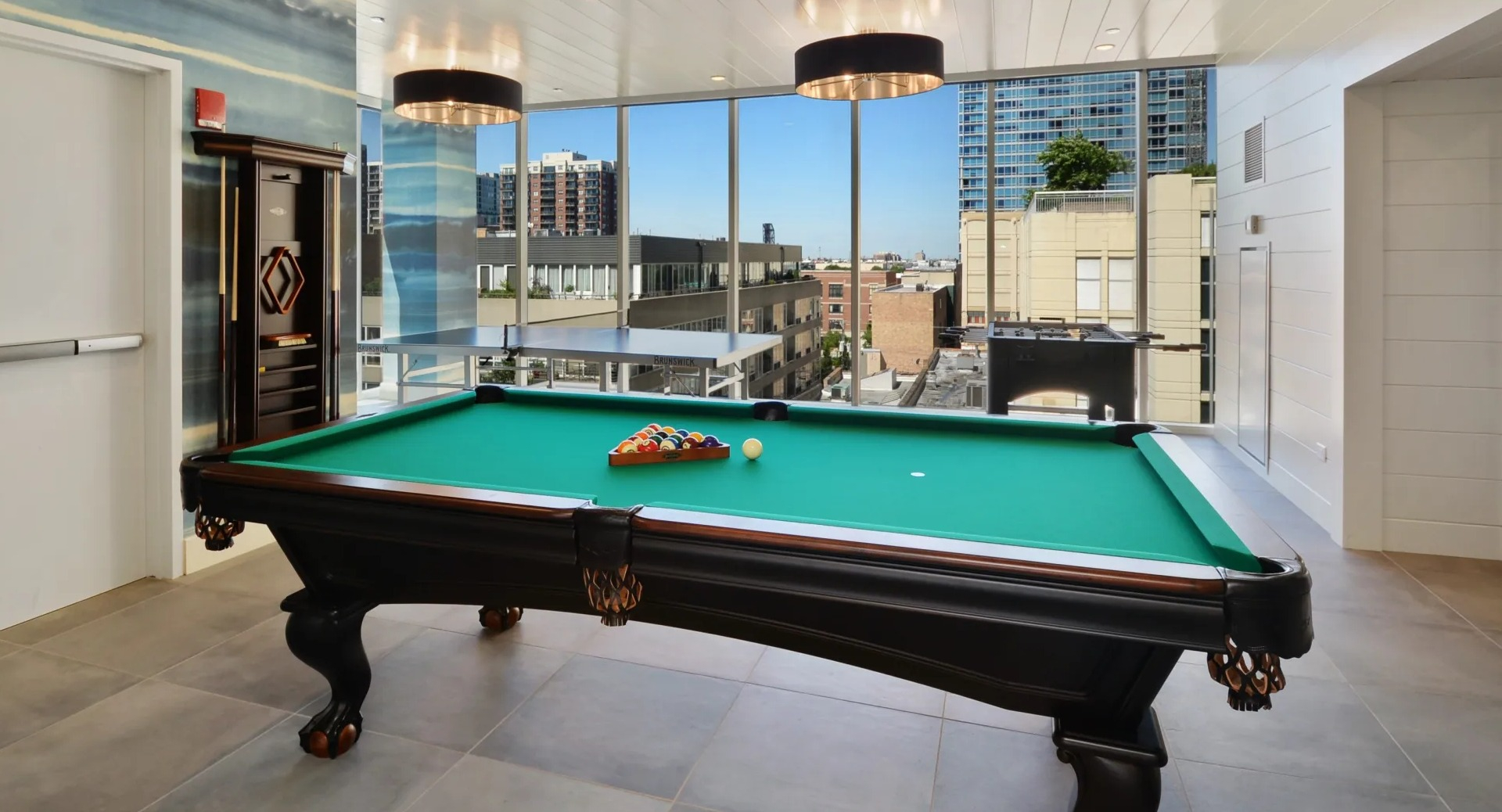 Resident clubroom with billiards table, statement pendants, and floor-to-ceiling windows overlooking the neighborhood at 1407 on Michigan in Chicago