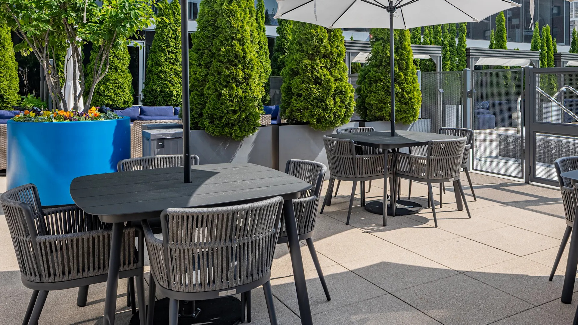 Outdoor dining terrace with umbrellas, modern tables, and lush planters next to the pool deck at 1407 on Michigan apartments in Chicago
