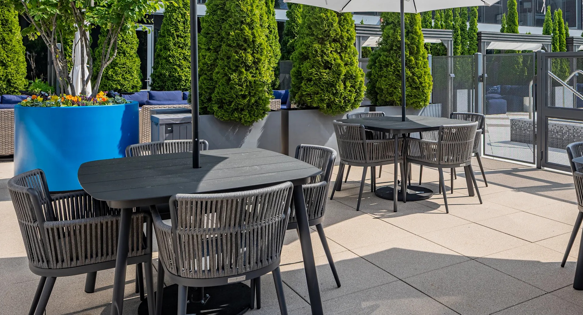 Outdoor dining terrace with umbrellas, modern tables, and lush planters next to the pool deck at 1407 on Michigan apartments in Chicago