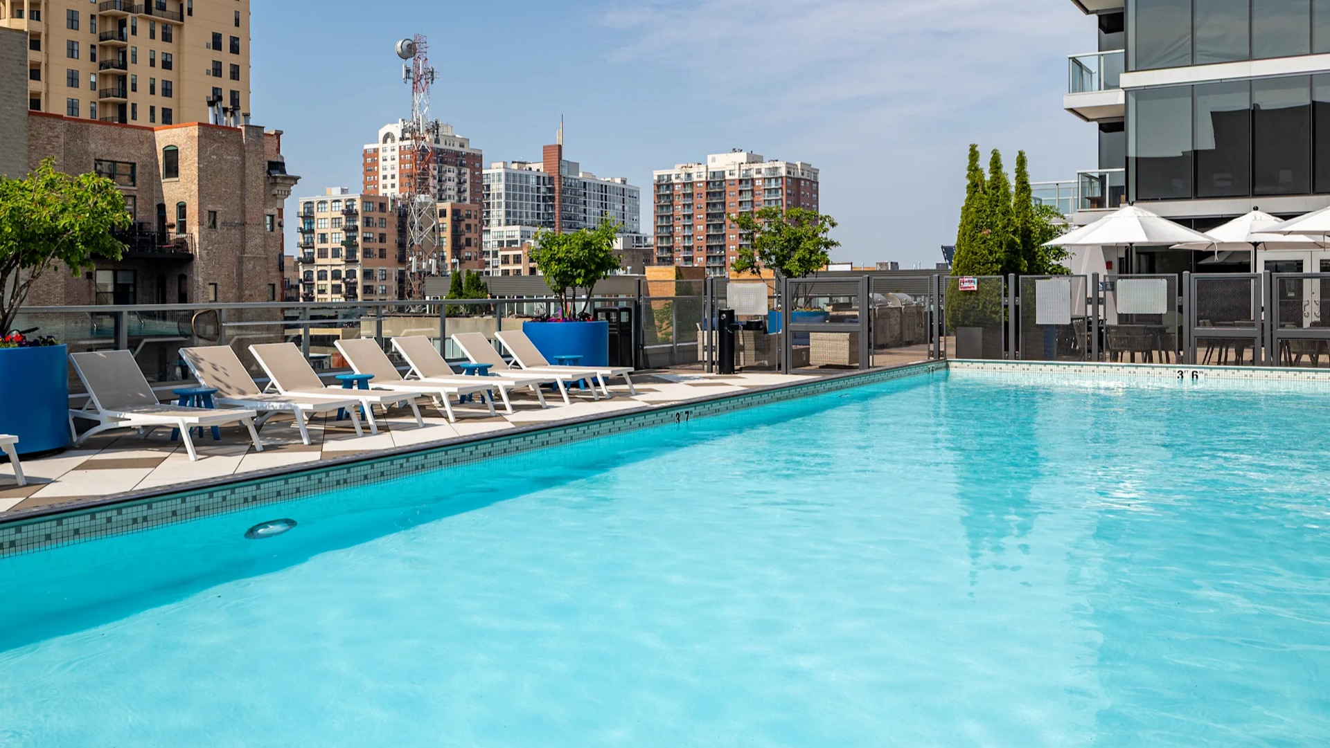 Sunny pool deck with lap pool, lounge chairs, planters, and skyline views at 1407 on Michigan apartments in Chicago