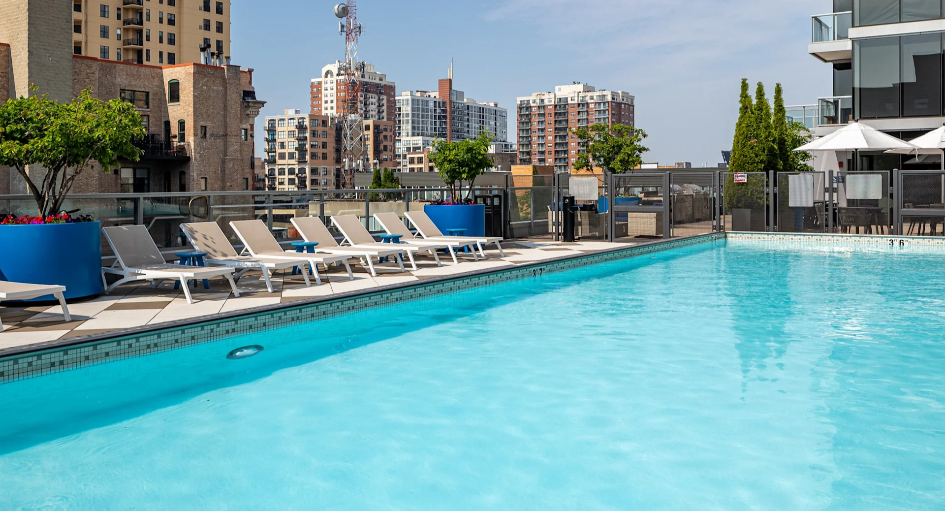 Sunny pool deck with lap pool, lounge chairs, planters, and skyline views at 1407 on Michigan apartments in Chicago