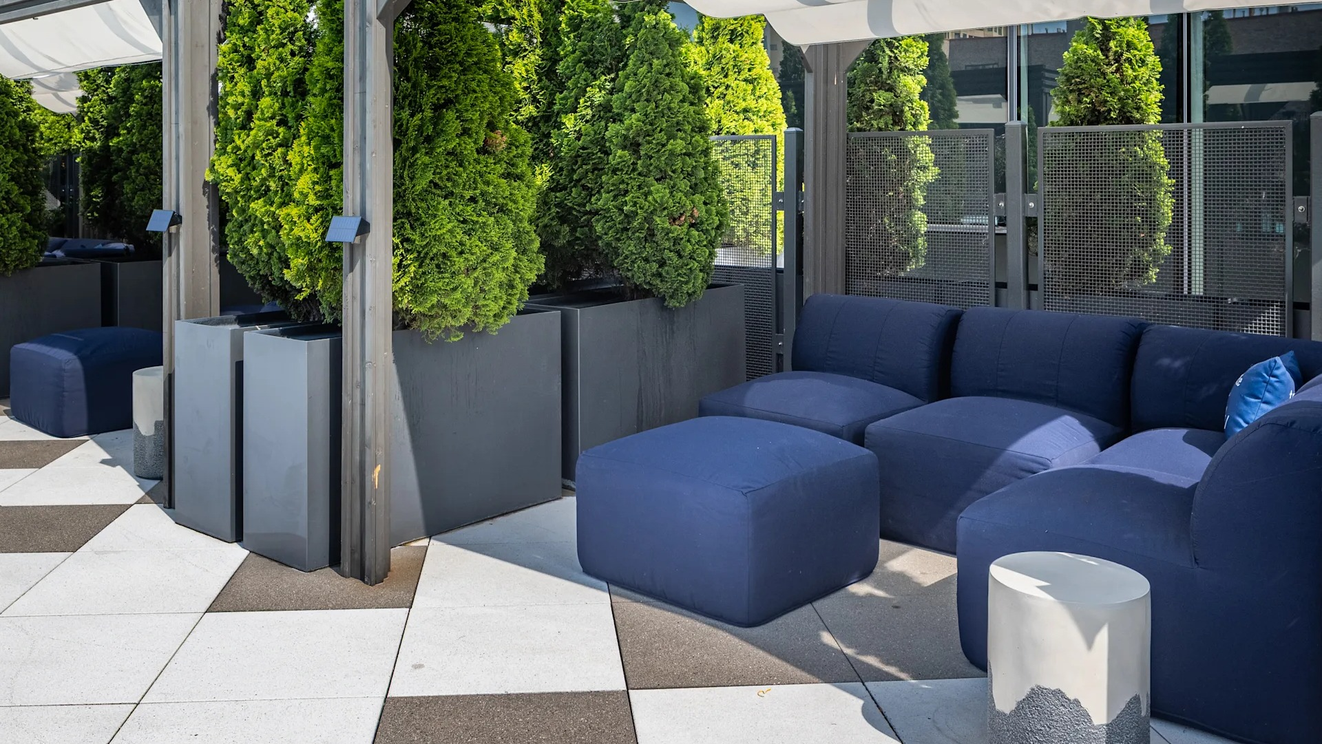 Private cabanas with deep-seat sofas, ottomans, and greenery along the pool terrace at 1407 on Michigan apartments in Chicago