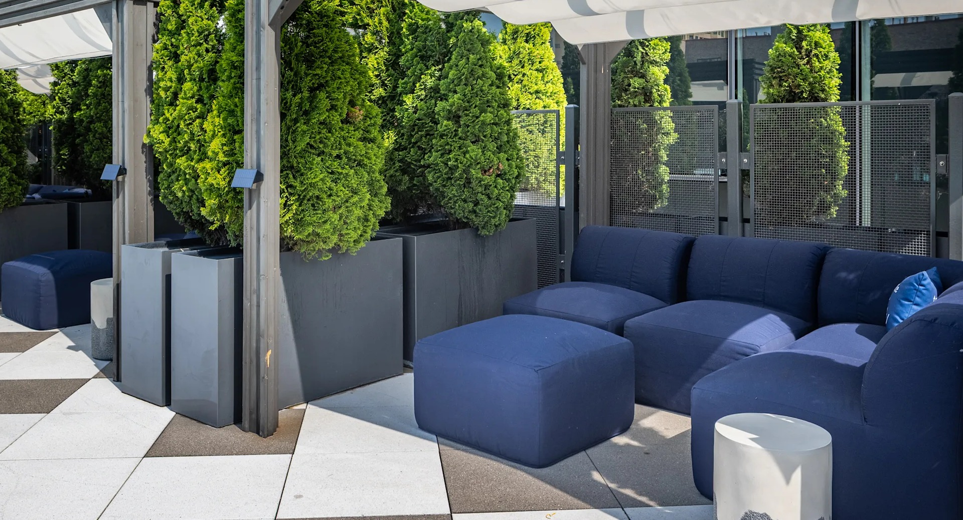 Private cabanas with deep-seat sofas, ottomans, and greenery along the pool terrace at 1407 on Michigan apartments in Chicago