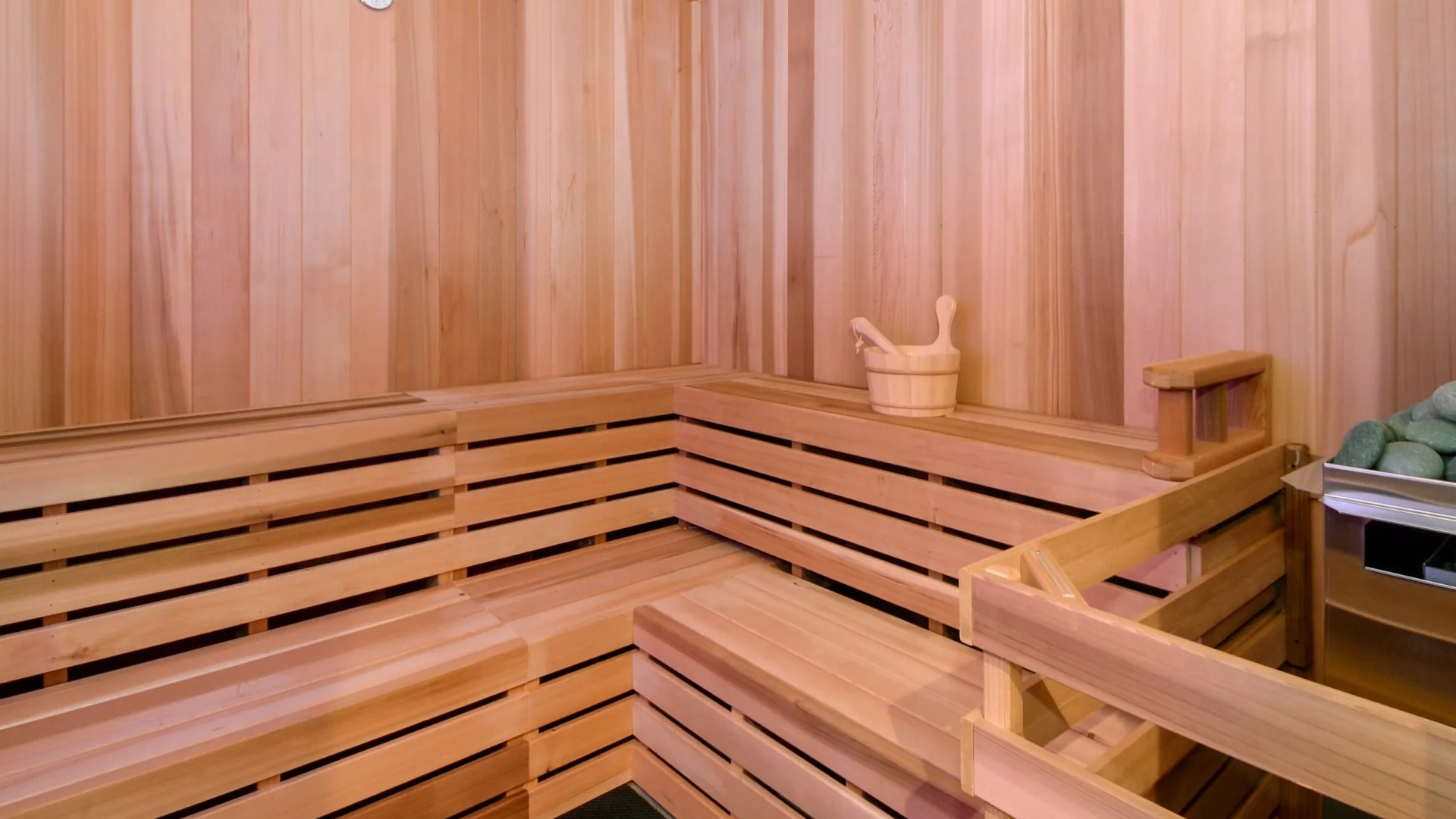 Cedar sauna with tiered benches, heater stones, and soft lighting at 1407 on Michigan apartments in Chicago