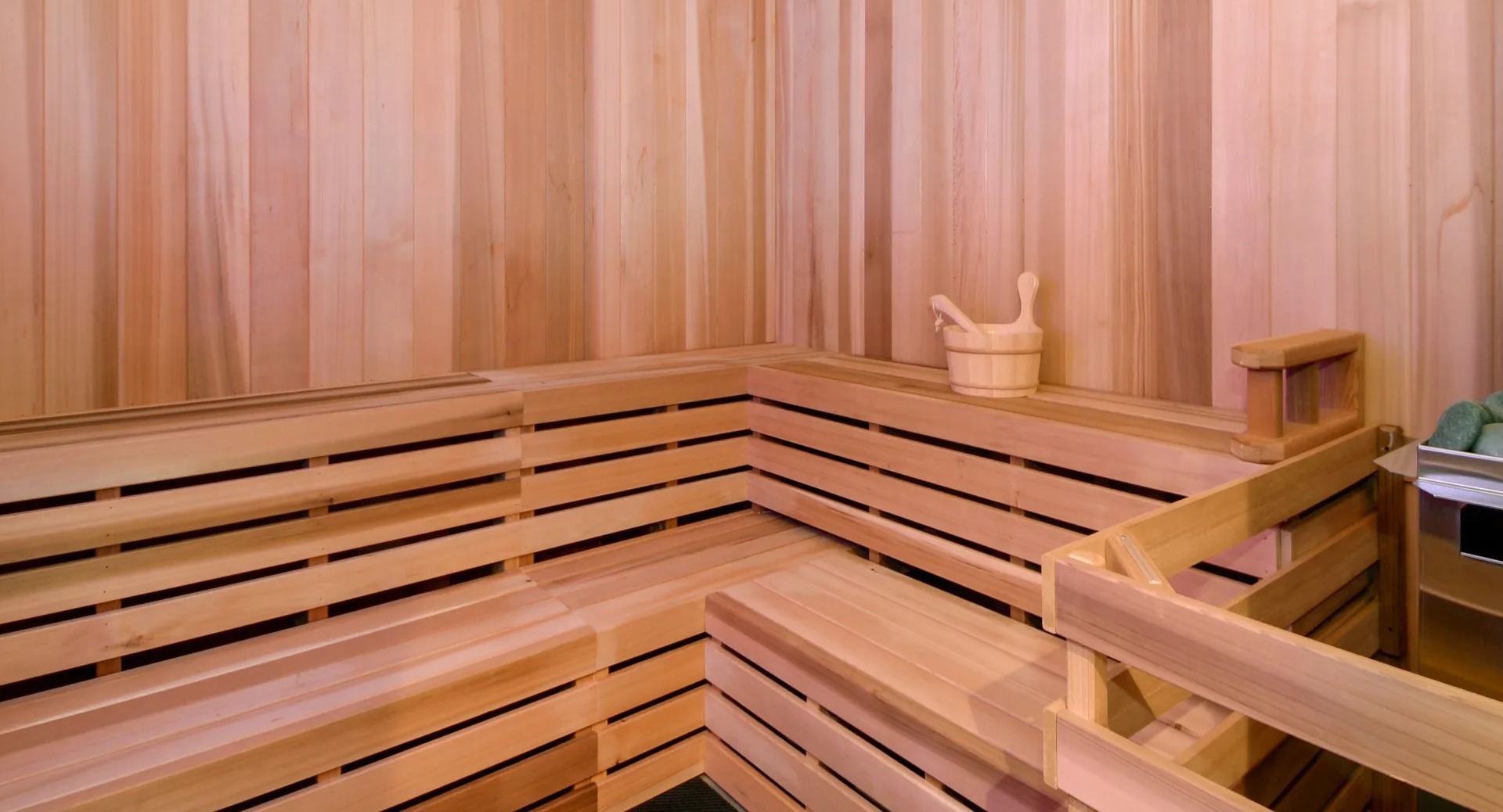 Cedar sauna with tiered benches, heater stones, and soft lighting at 1407 on Michigan apartments in Chicago
