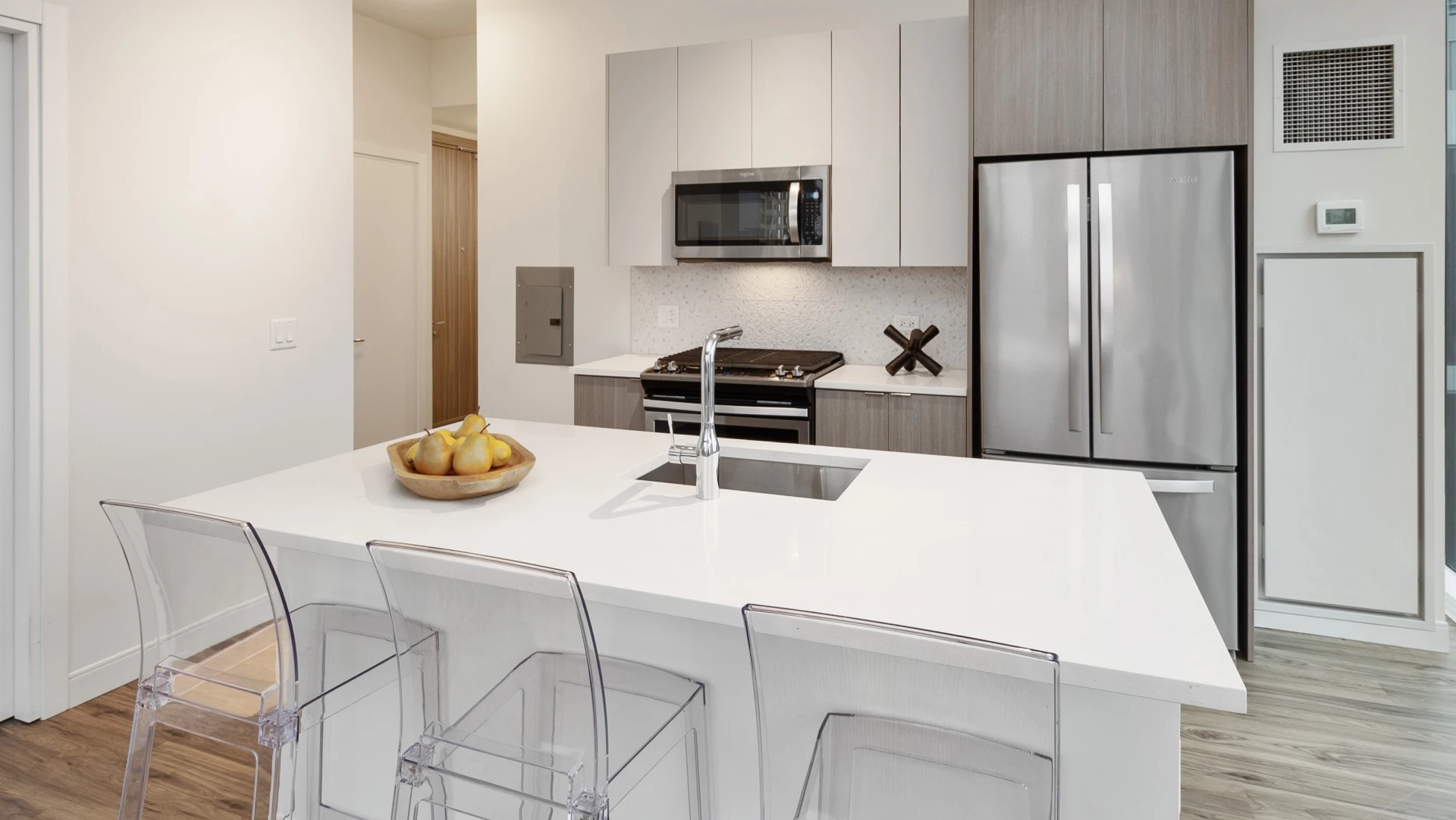 Contemporary kitchen with white quartz island, gas range, microwave, and stainless fridge at 1407 on Michigan apartments in Chicago