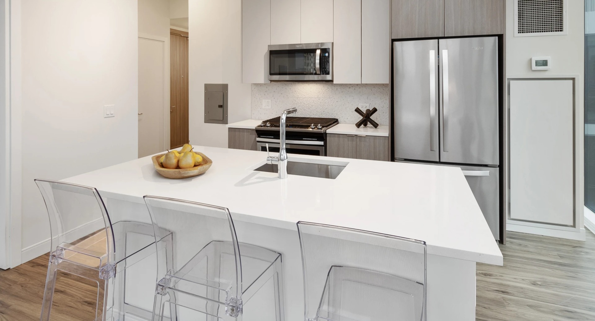 Contemporary kitchen with white quartz island, gas range, microwave, and stainless fridge at 1407 on Michigan apartments in Chicago