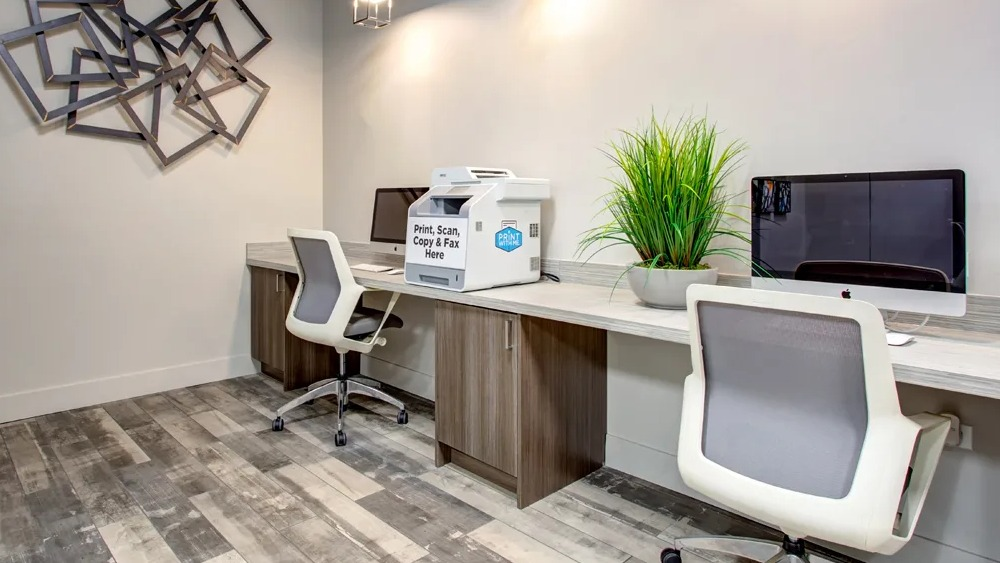 Resident business center with iMac computers, a print-scan-copy station and modern task chairs at 180 North Jefferson apartments in Chicago