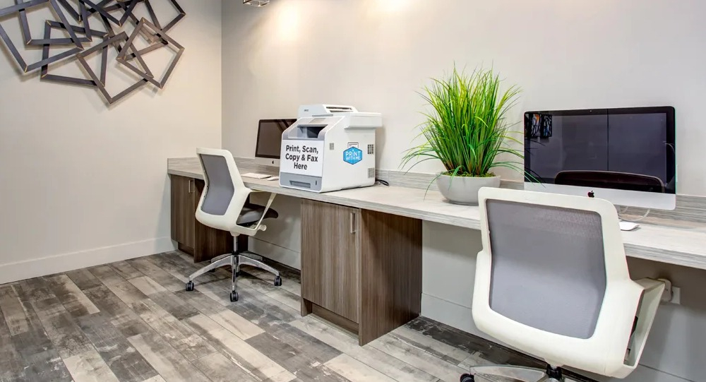 Resident business center with iMac computers, a print-scan-copy station and modern task chairs at 180 North Jefferson apartments in Chicago